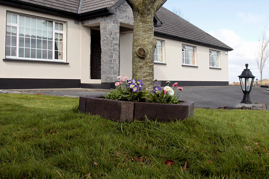 Recycled plastic tree surround planted with flowers at the base of a tree